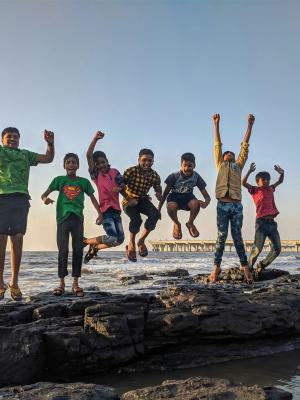 Junge Trägt Grünes Hemd Mit Rundhalsausschnitt, Das Vom Schwarzen Stein An Der Küste Springt